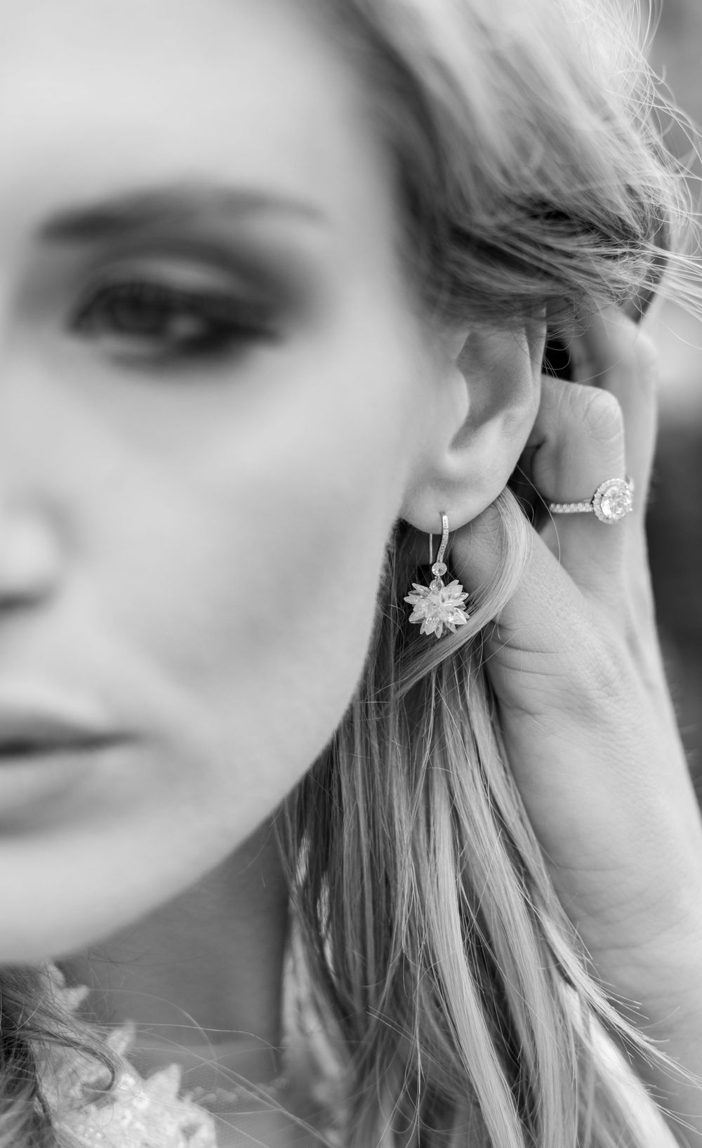 Artistic black and white macro shot of floral earring and makeup details.