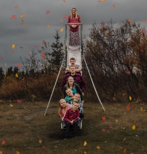 A whimsical slide portrait with falling autumn leaves against a moody gray sky.