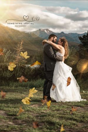 Romantic wedding photo with couple embracing against mountain backdrop as autumn leaves float past.