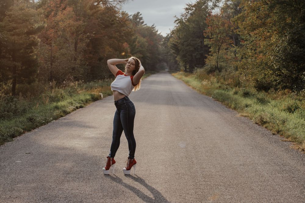 Silhouette of person posing on empty country road during autumn season.