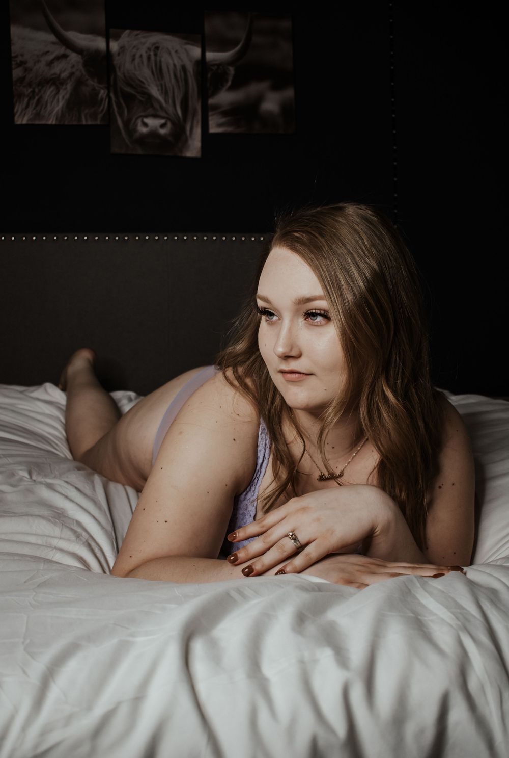 Intimate boudoir photo of person resting on white bedding.