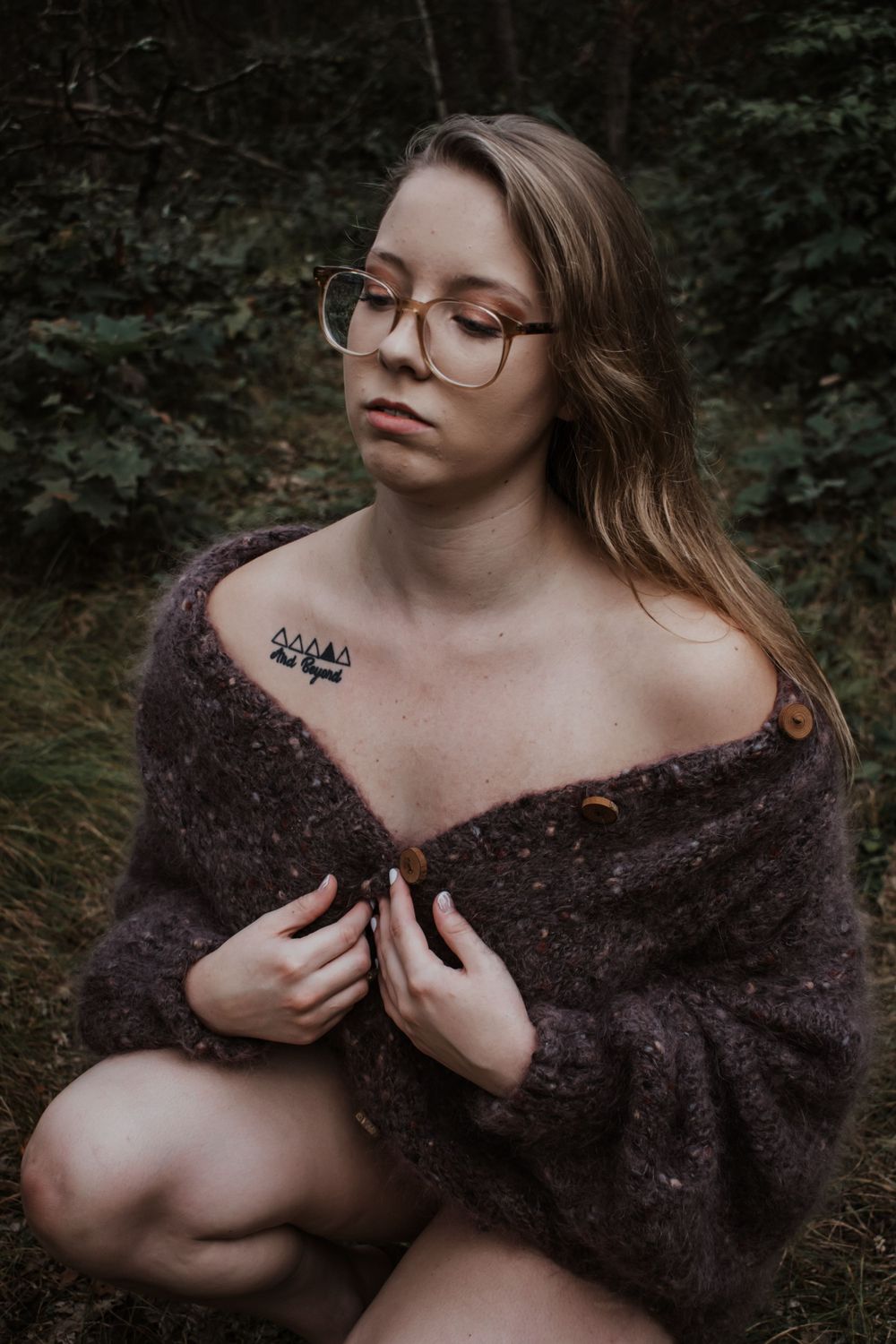 Moody forest portrait in knit sweater showing shoulder tattoo detail.