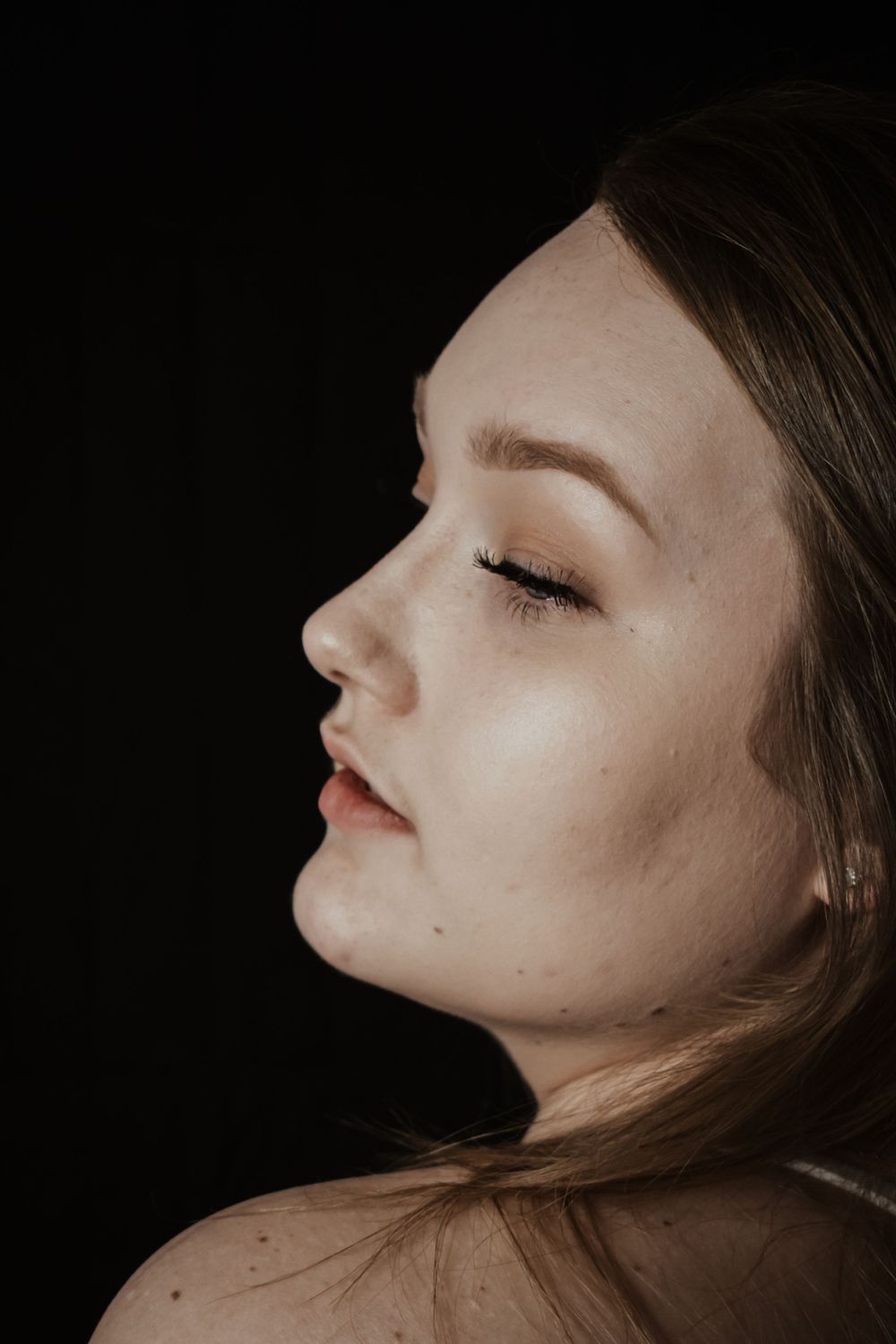 Side profile portrait in moody black and white lighting.