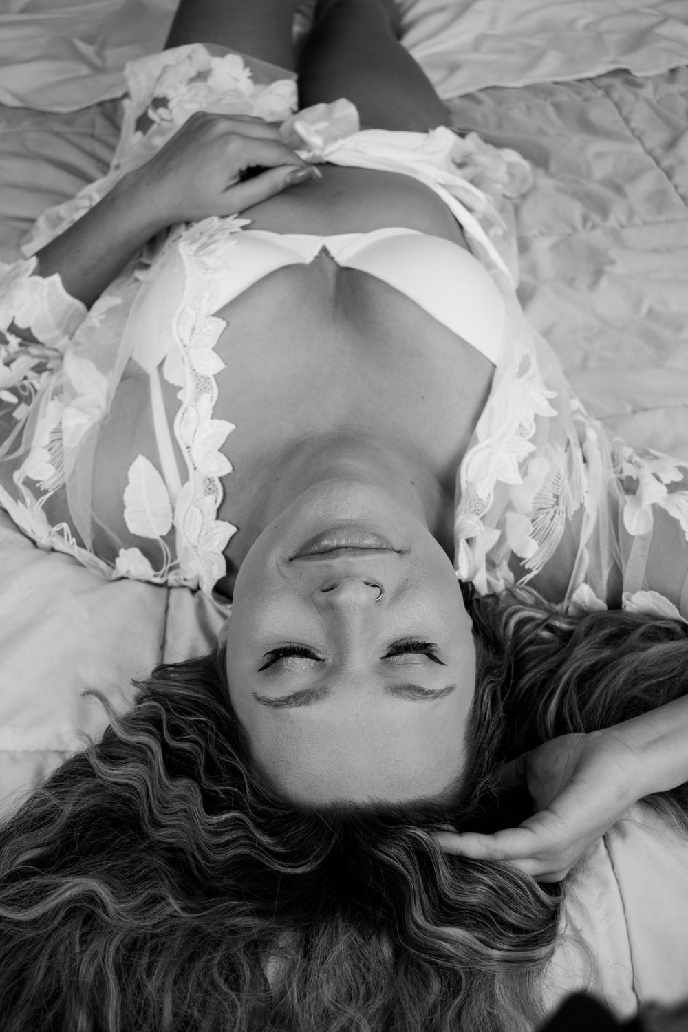 Person lying on white sheets with scattered paper decorations in monochrome.