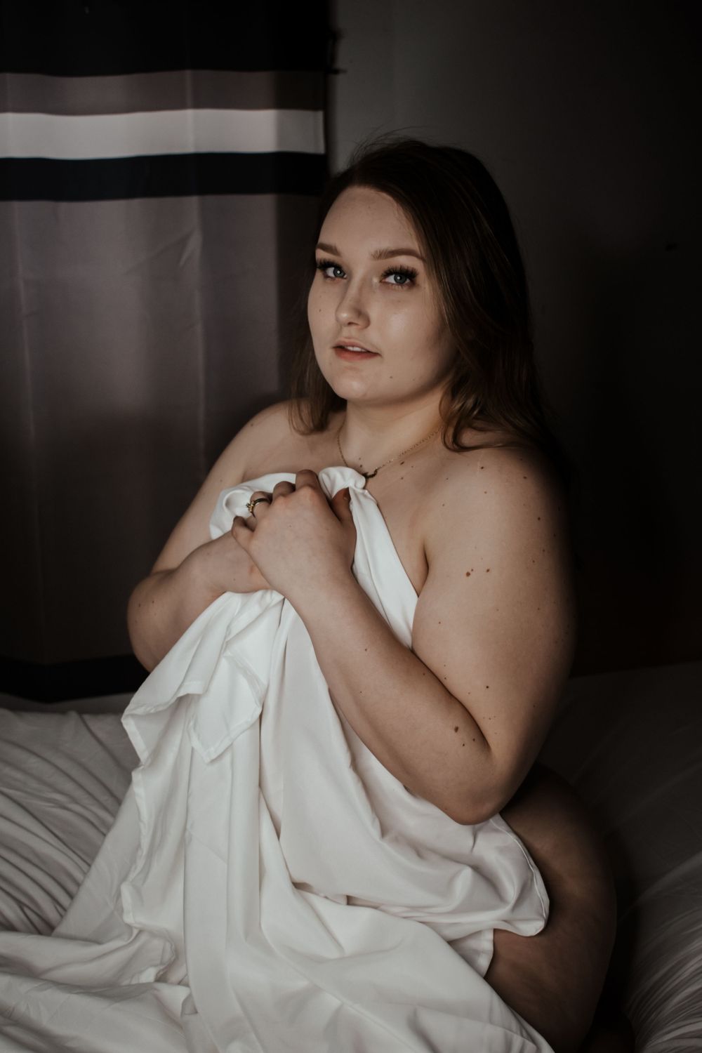 Artistic portrait in white fabric with dramatic shadows and lighting.