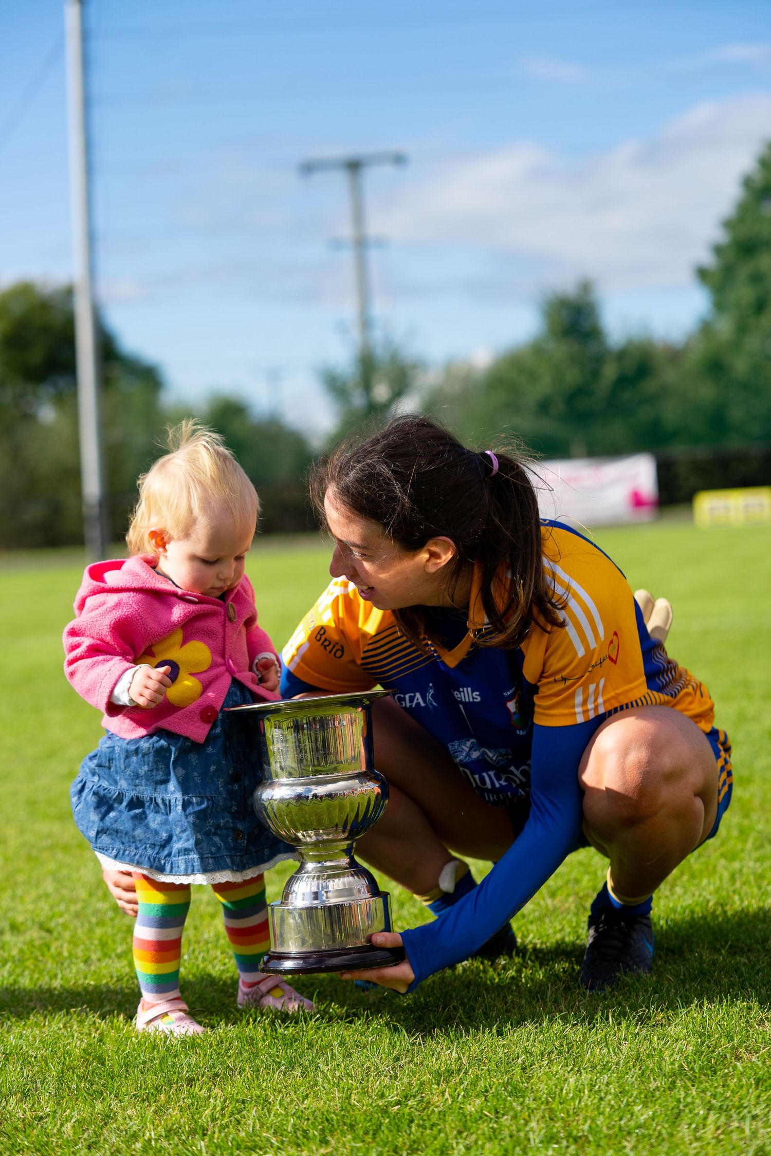 A small child and athlete looking at a trophy on a sports field.