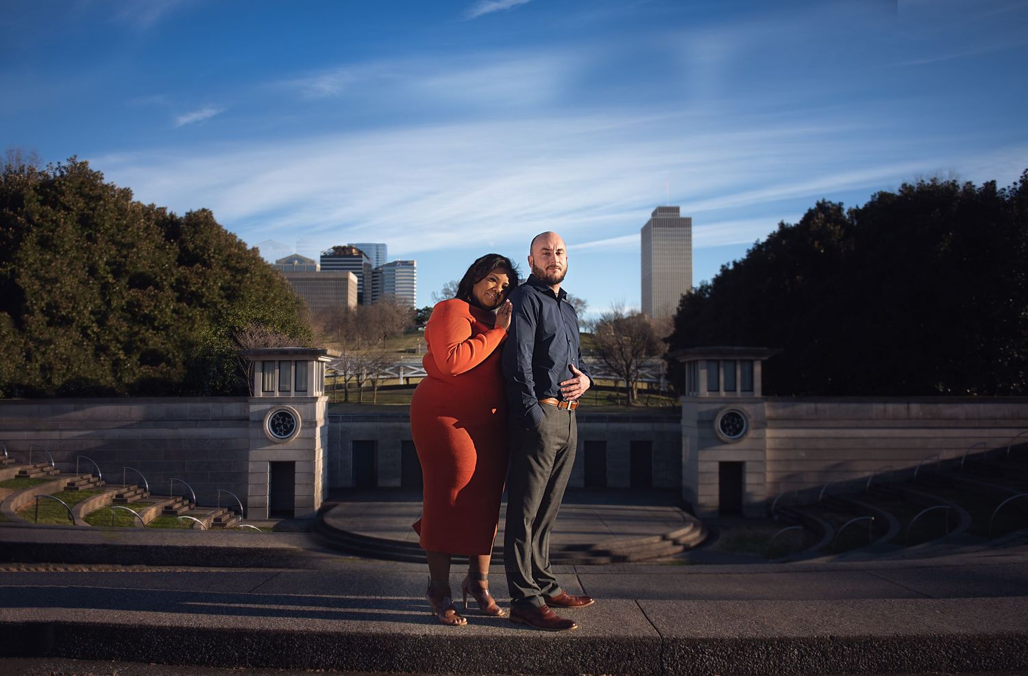 A romantic proposal taking place on a bridge with an urban skyline in the background.