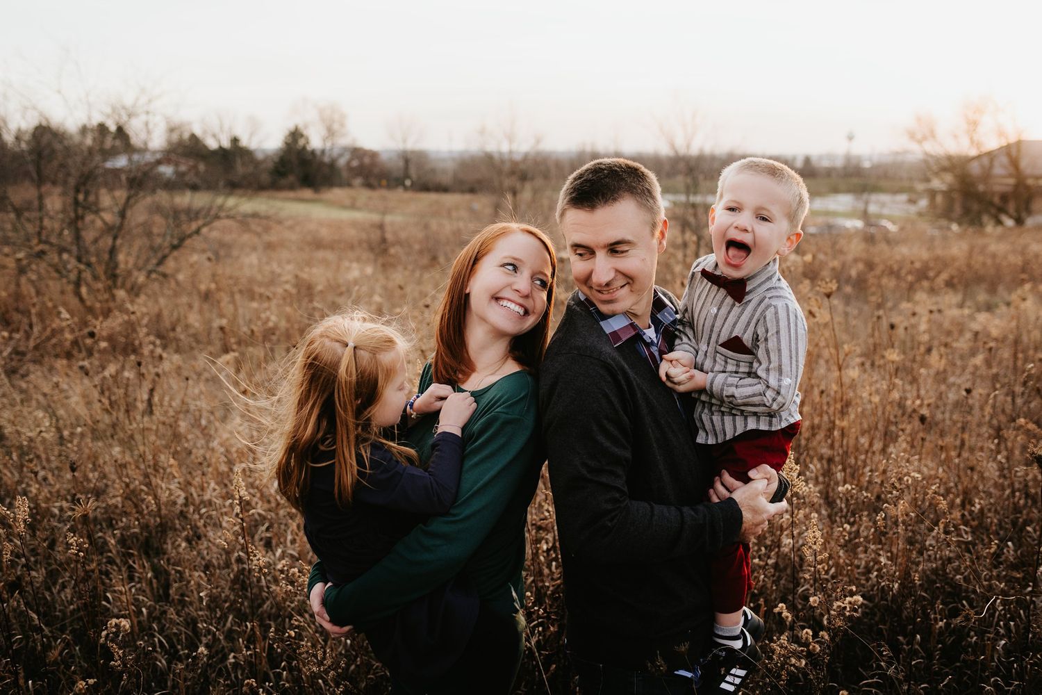 A playful family portrait in a natural outdoor setting with golden autumn light.