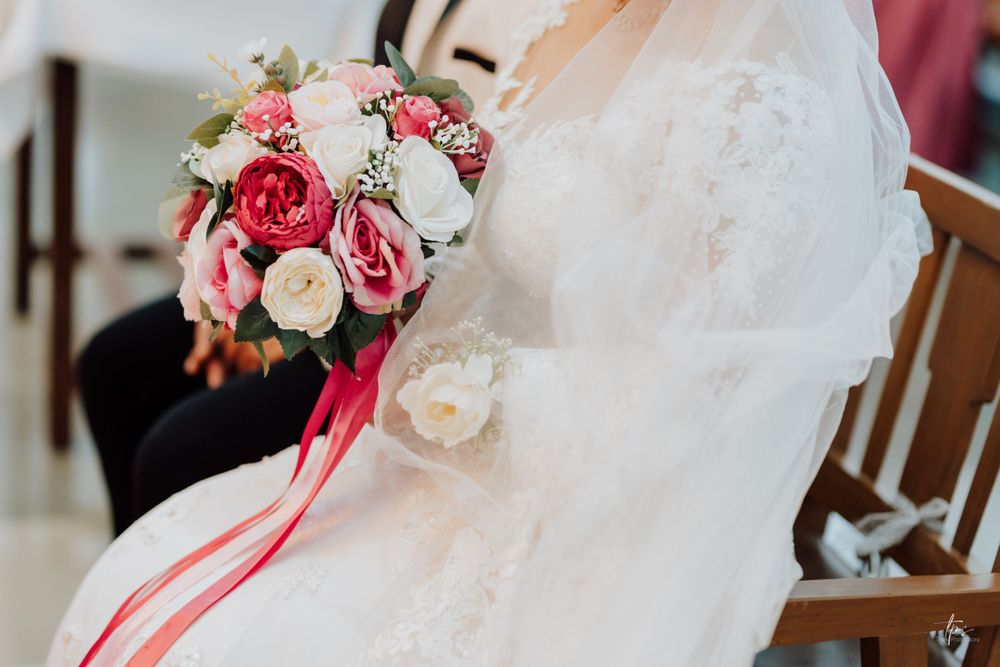 Pink and white floral bouquet with roses against white fabric background.