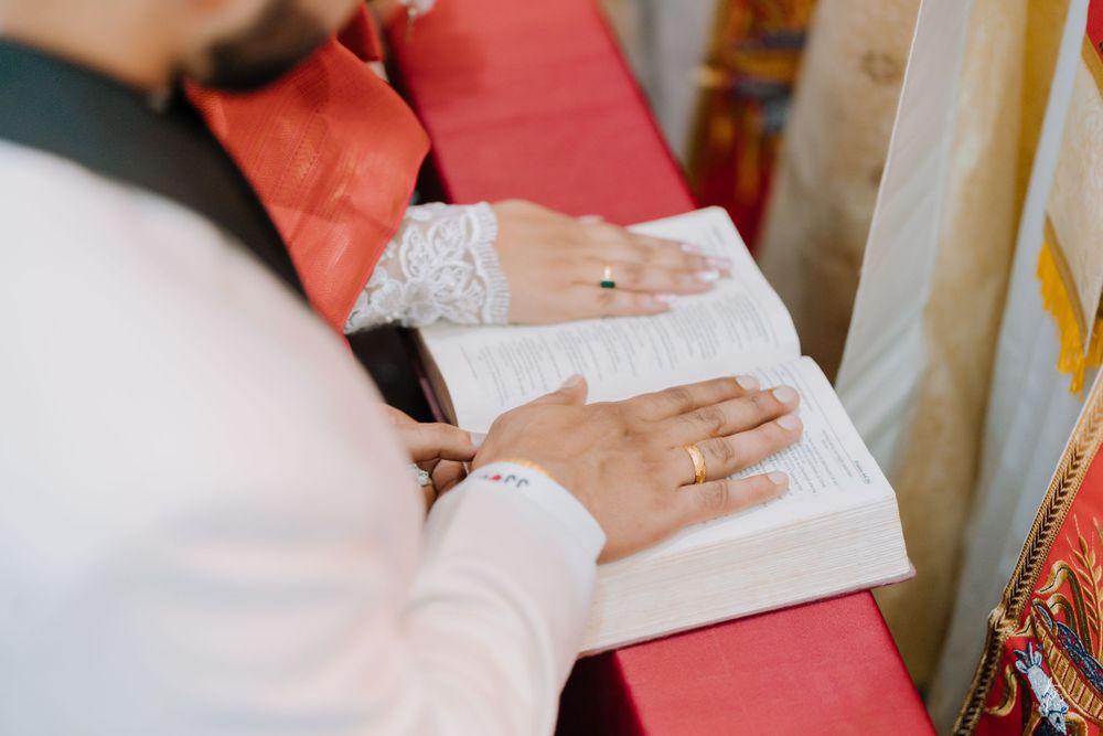 Couple signing wedding documents on a red table during their ceremony.