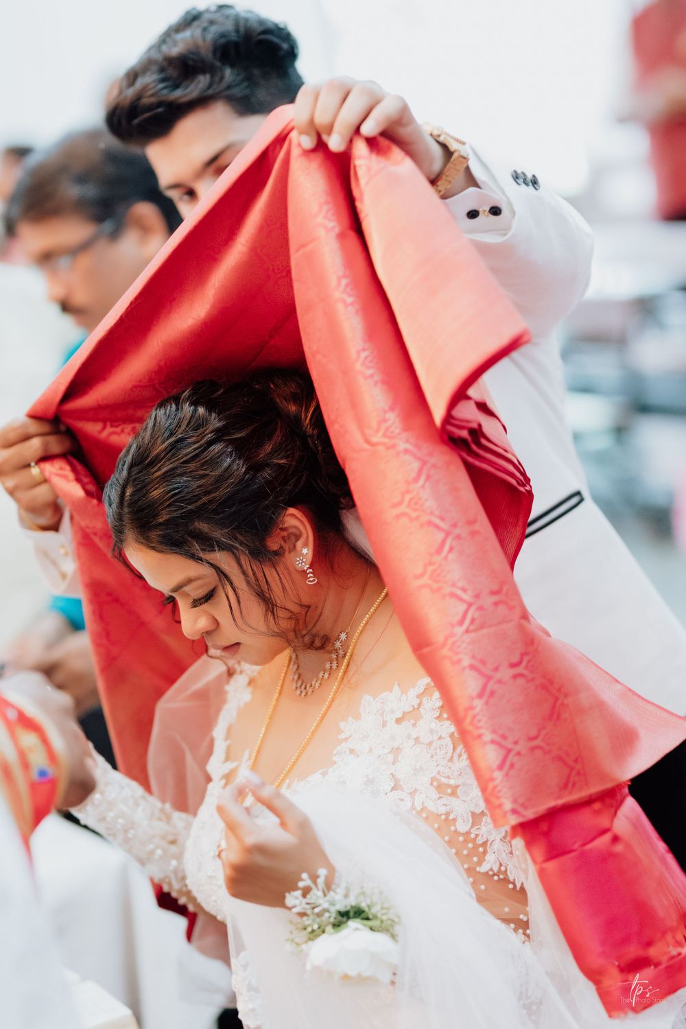 Wedding guests hold red ceremonial cloths during a traditional church service.