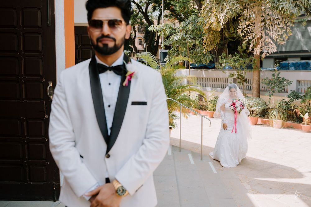 Groomsmen in white tuxedos and black bowties pose outside venue.