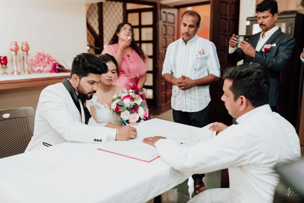 Wedding party members sign official documents at reception tables.