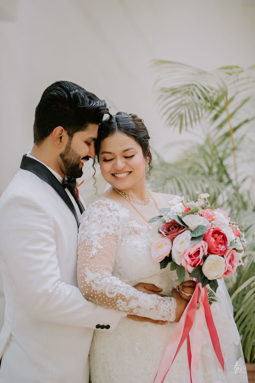 Romantic wedding couple shares intimate moments while holding pink and white floral bouquet.