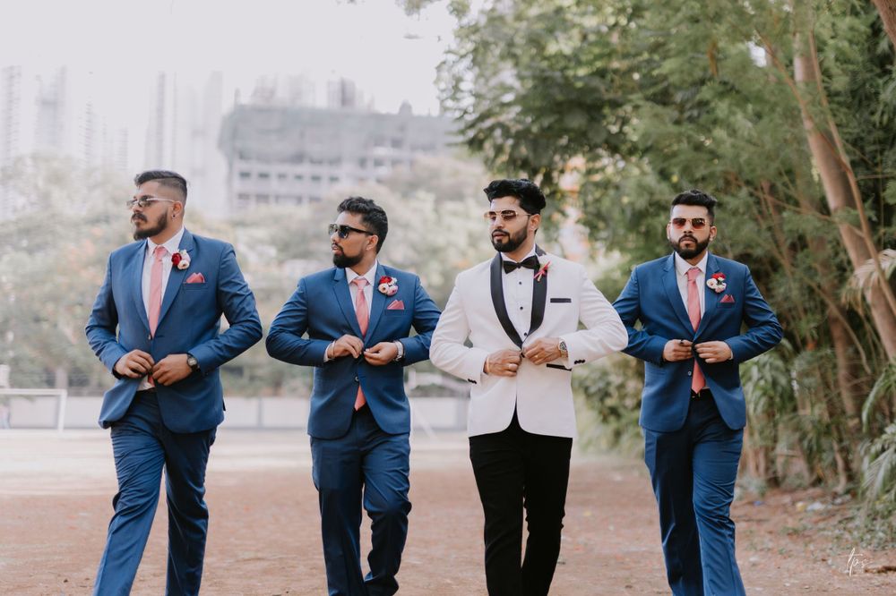 Groomsmen in navy suits pose outdoors for wedding photos.