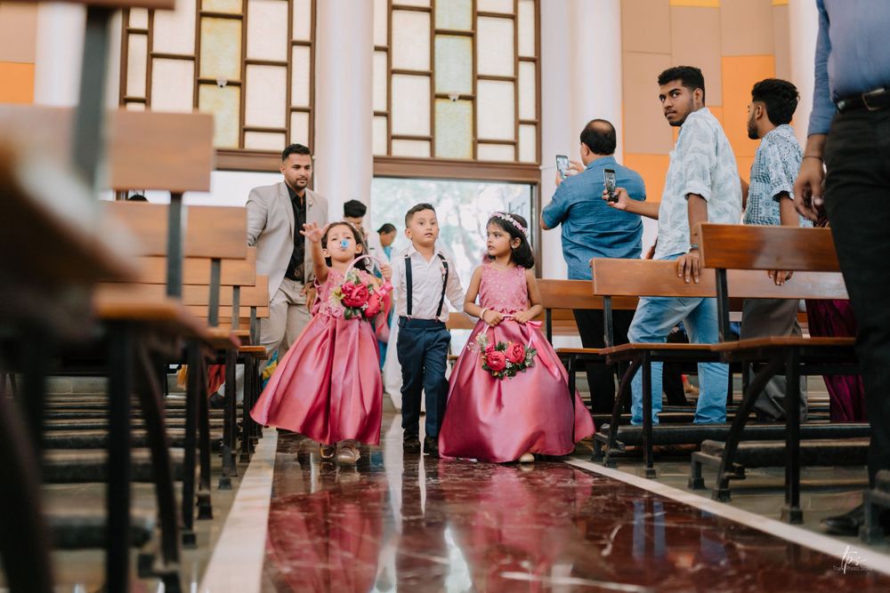 Wedding party members in pink dresses seated in church pews.