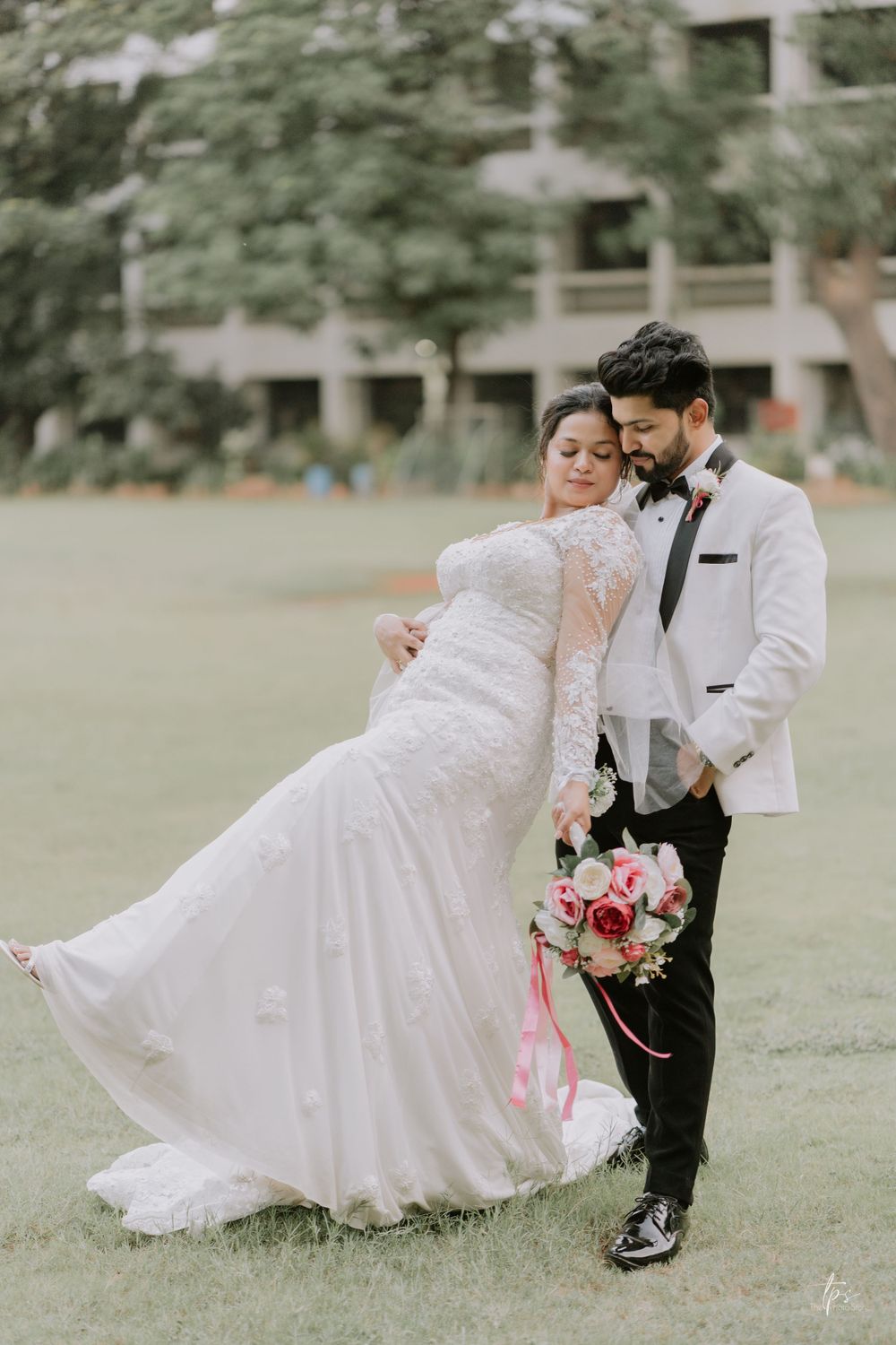 Wedding couple performing romantic dance moves on green lawn with elegant poses.