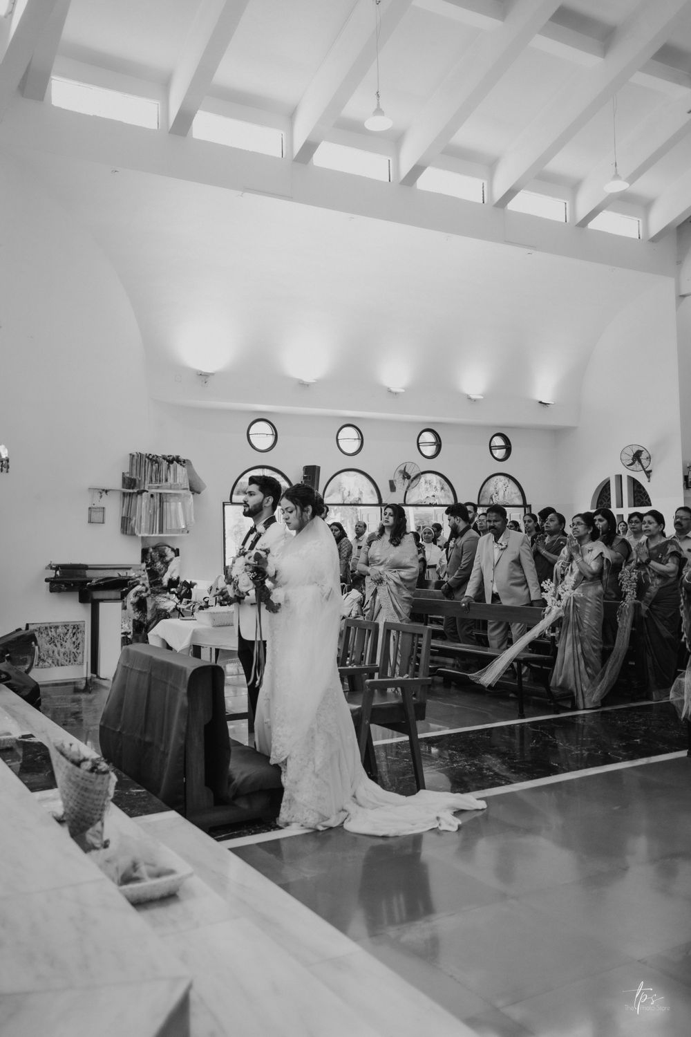 Black and white photo of wedding reception in spacious church hall.