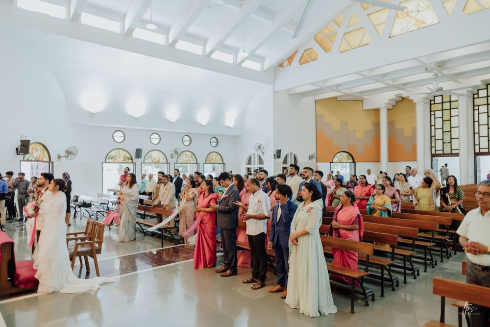Wide angle view of church wedding ceremony with guests seated in pews.