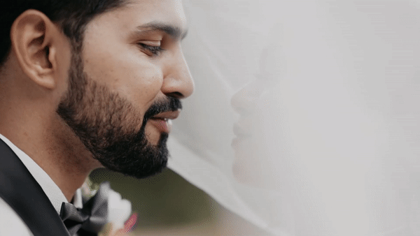 Close-up profile shot of a groom in formal attire against light background.