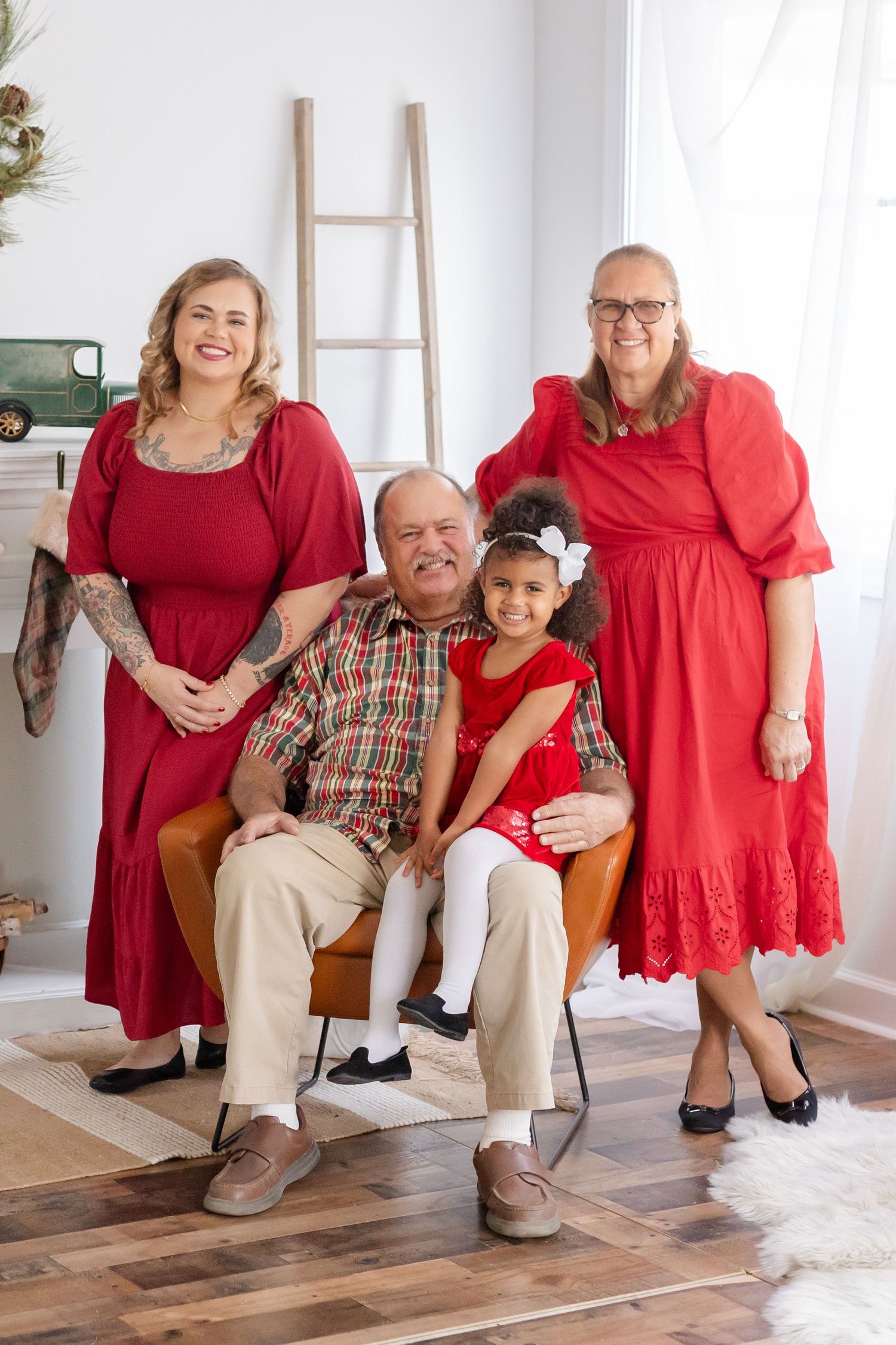 A group in red holiday outfits poses together in a bright room with Christmas decorations.