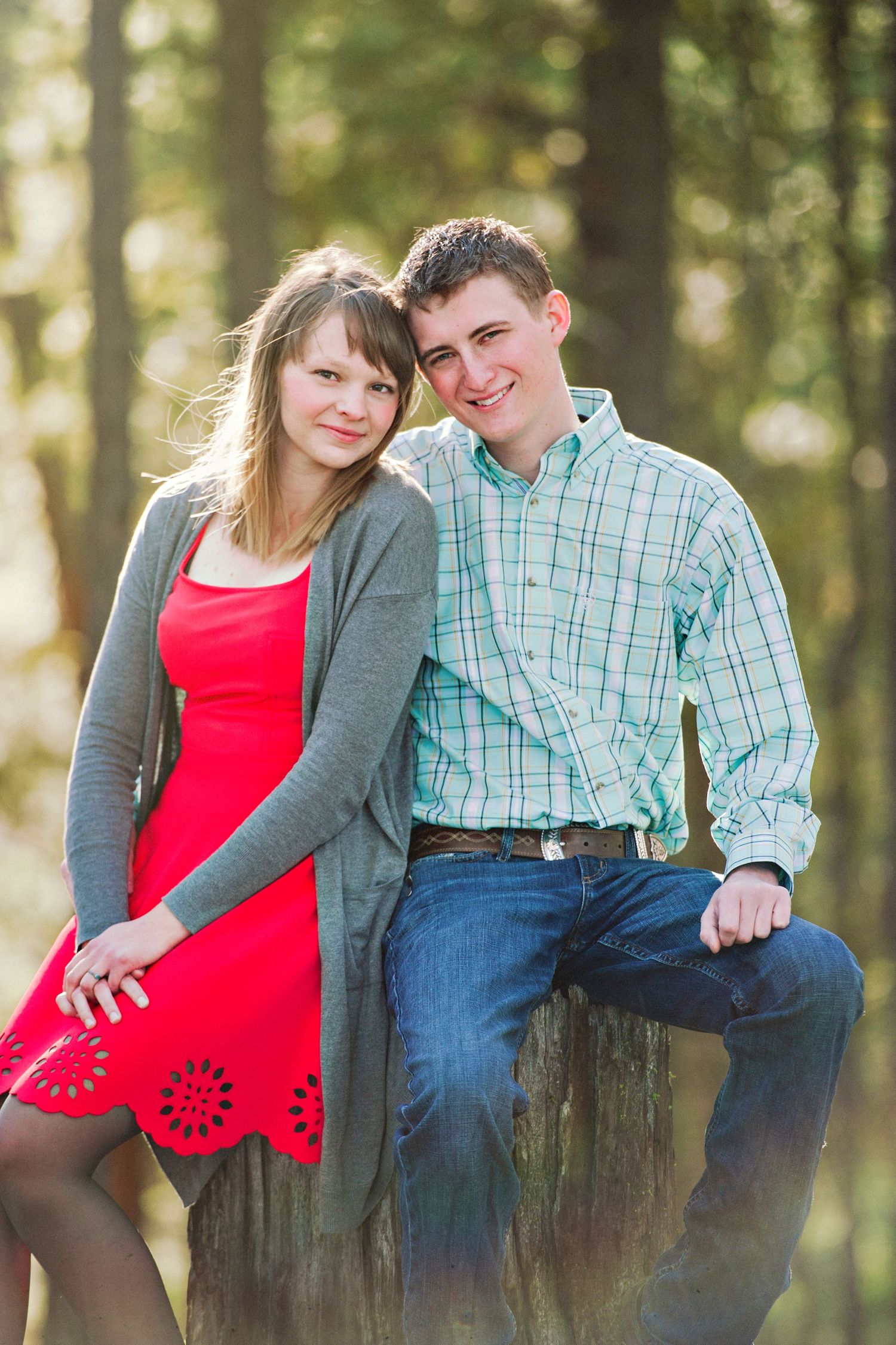 A young couple sits on a stump in the woods near Sumpter, Oregon