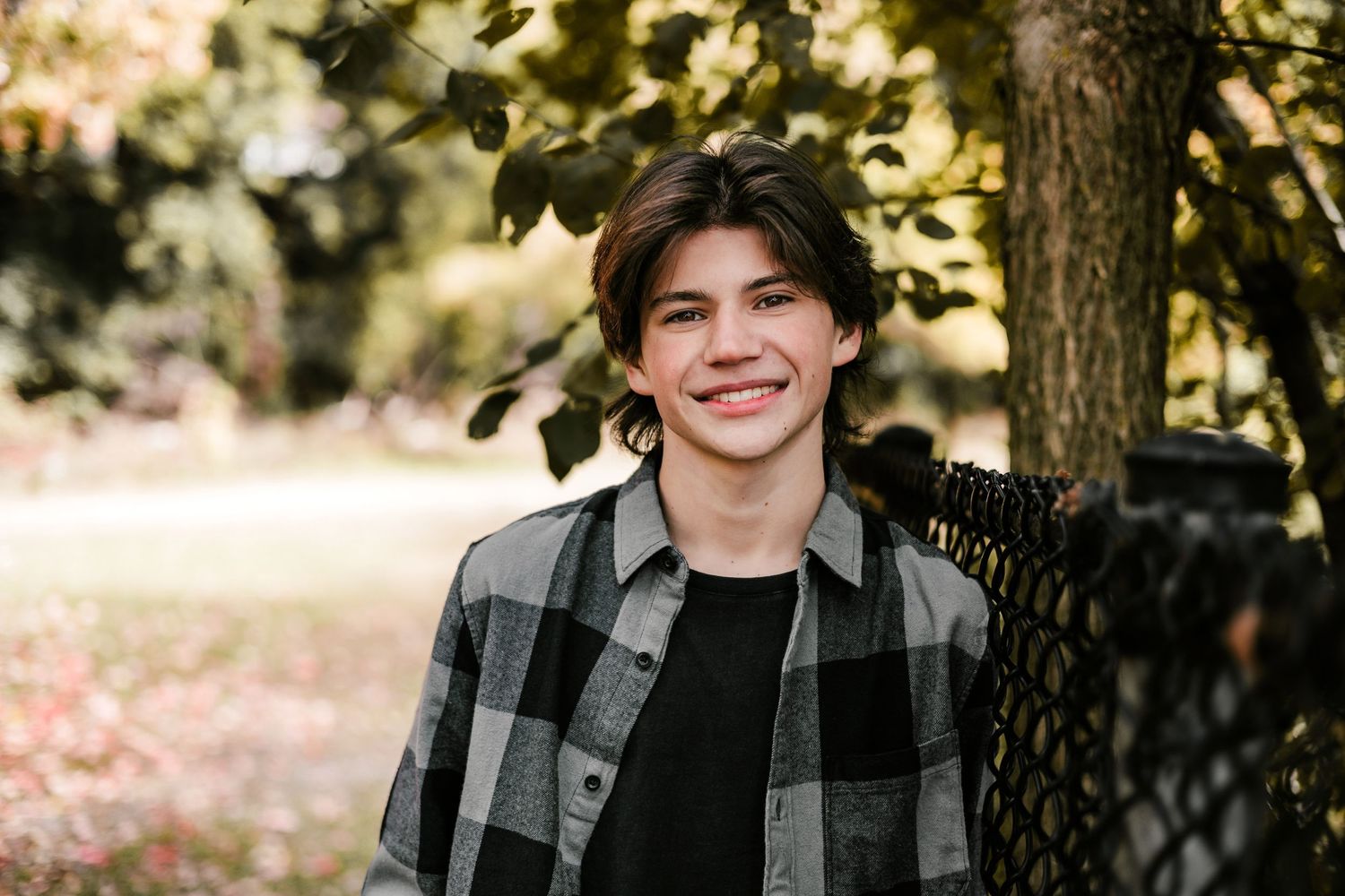 Outdoor portrait wearing black and grey plaid shirt in autumn setting.