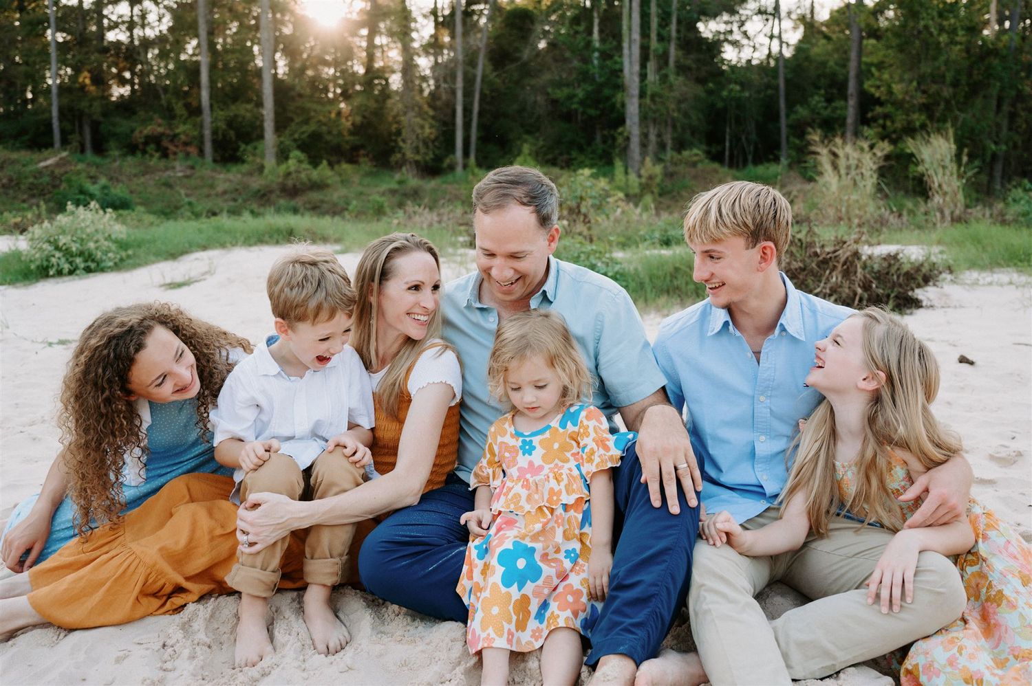 A family enjoys a casual moment together during a sunset photo session outdoors.