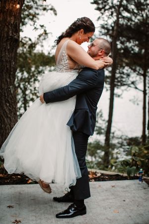 Romantic wedding portrait of couple embracing with the groom lifting the bride in her flowing dress.