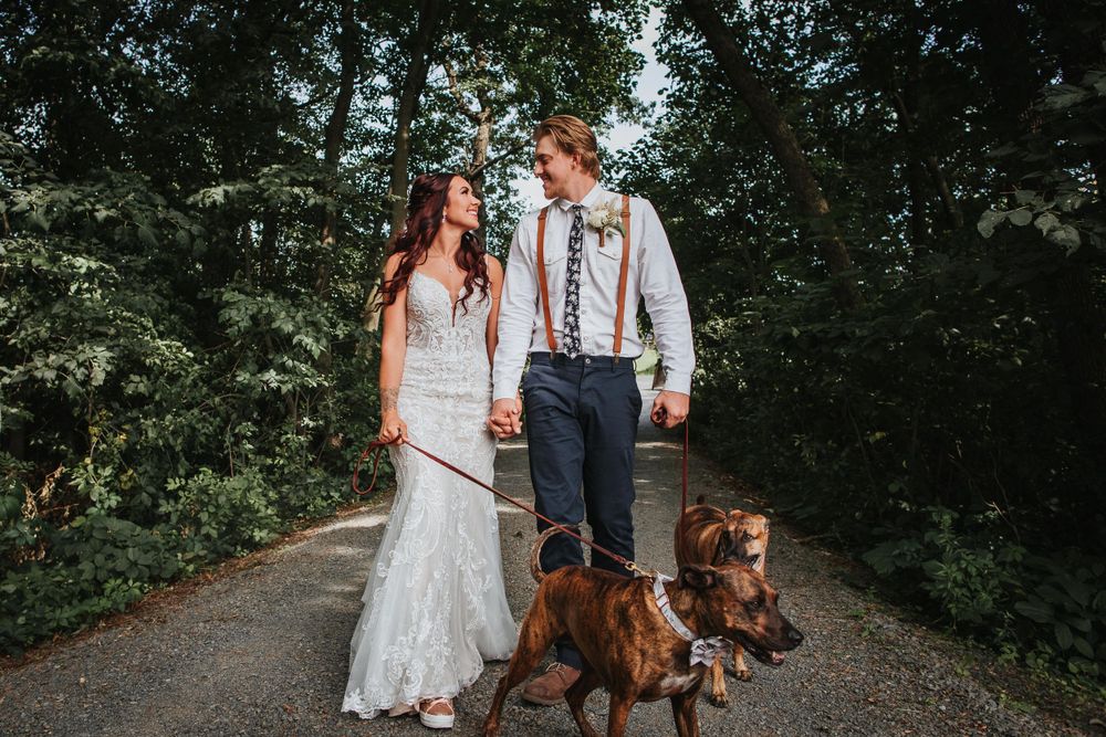 Wedding party creating celebratory arch tunnel for newlyweds on outdoor path.