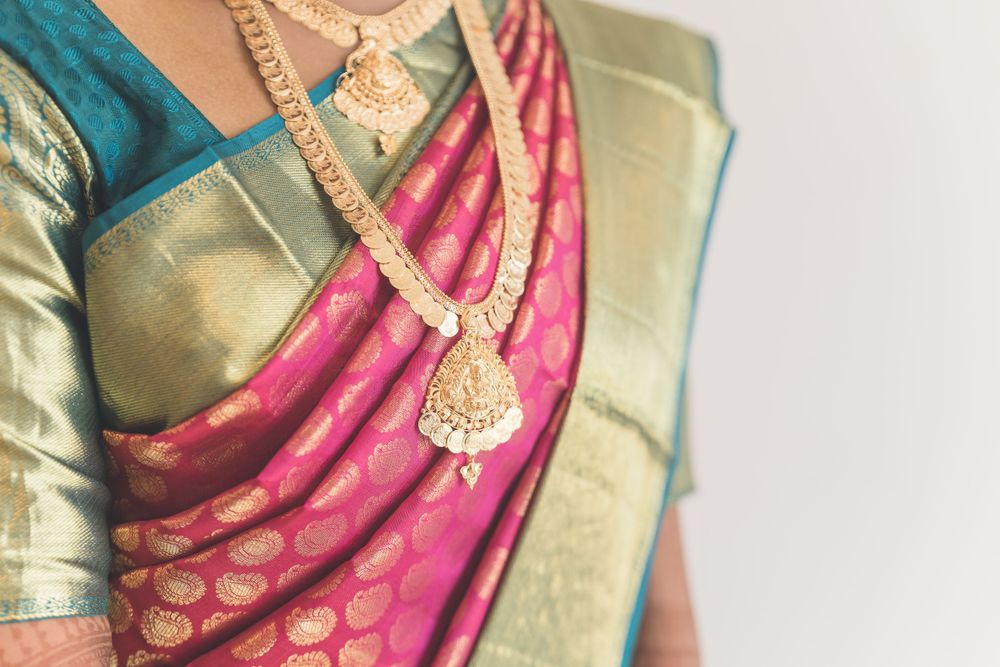 Close-up of traditional gold necklace and silk saree with intricate border design.