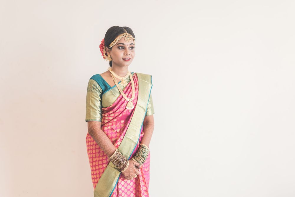 Traditional South Indian bridal attire featuring a pink and gold silk saree with elegant jewelry.