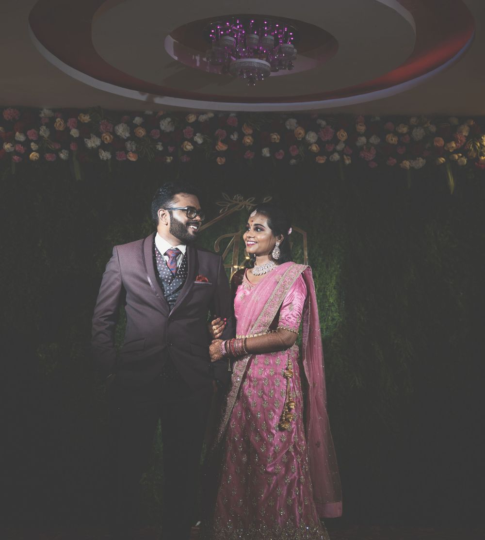 Artistic low-light portrait of a couple in traditional Indian wedding attire under decorative lighting.