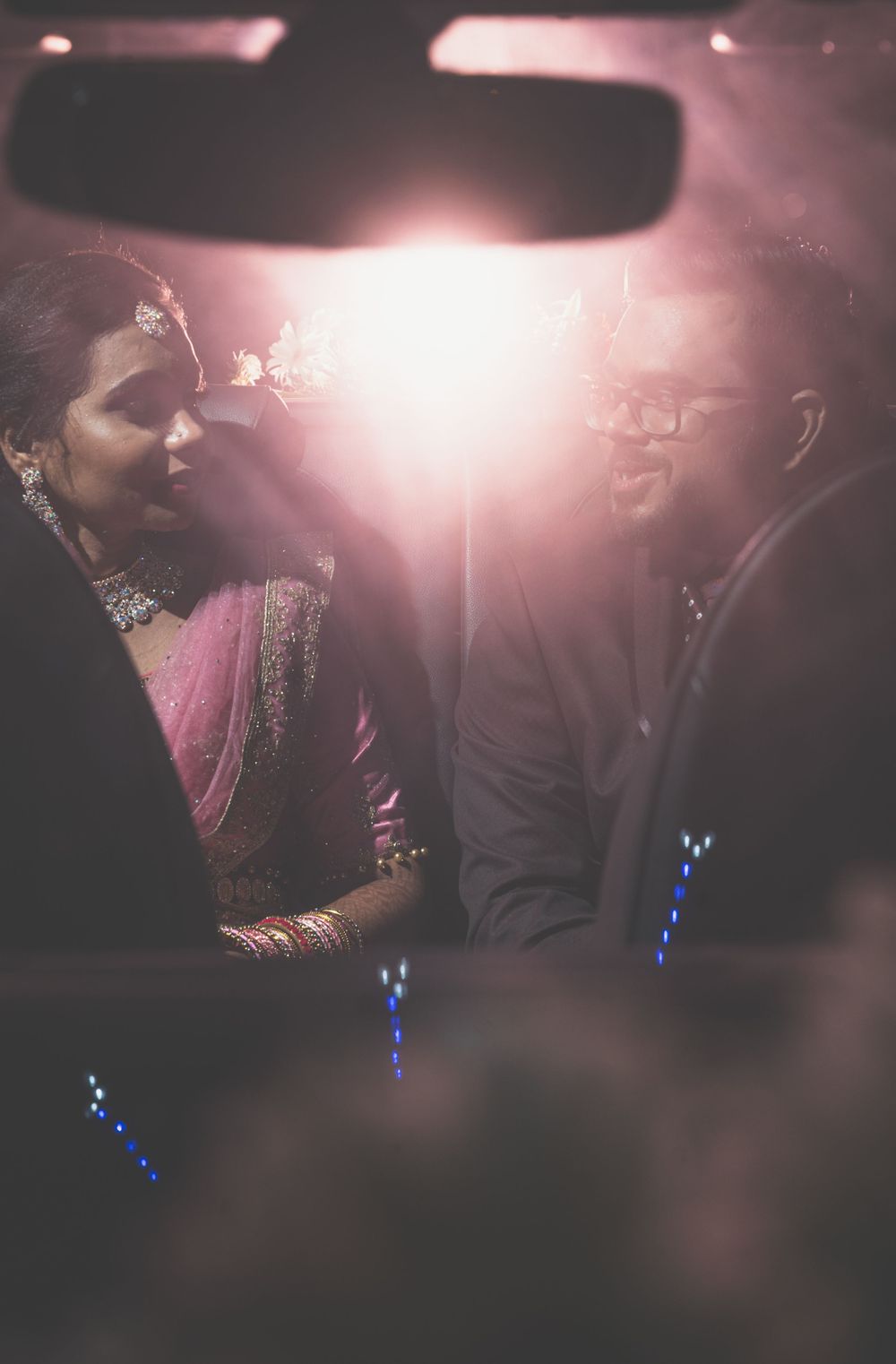 A romantic silhouette of a couple in a car illuminated by soft pink lighting.