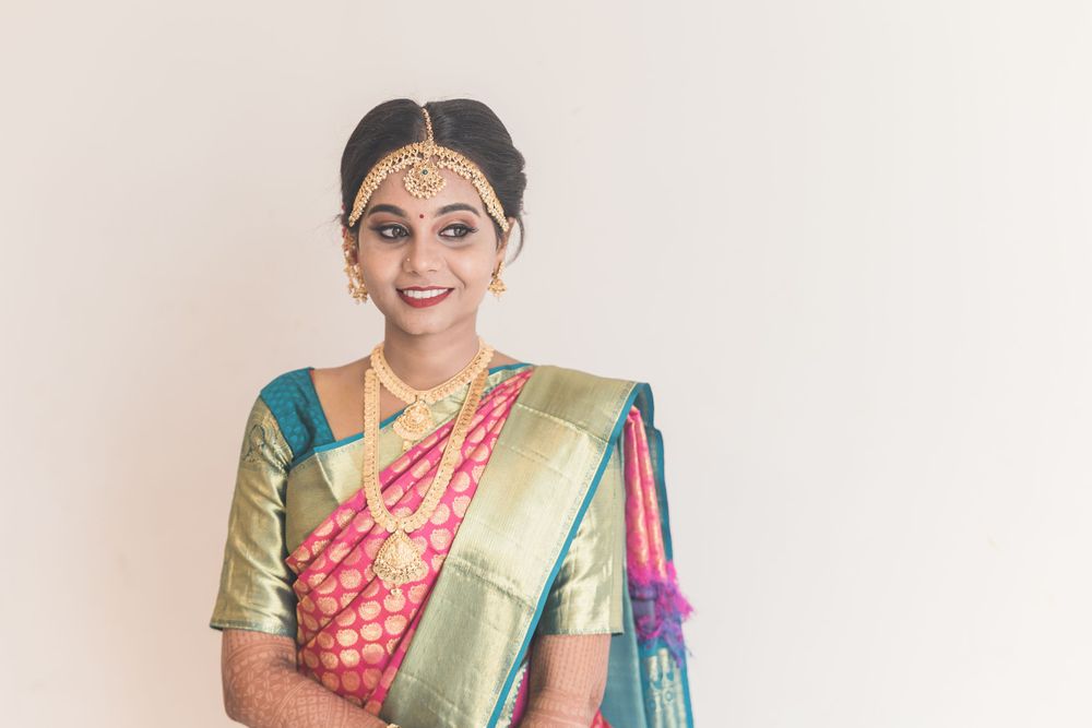 Traditional bridal look with silk saree and ornate gold jewelry against white background.
