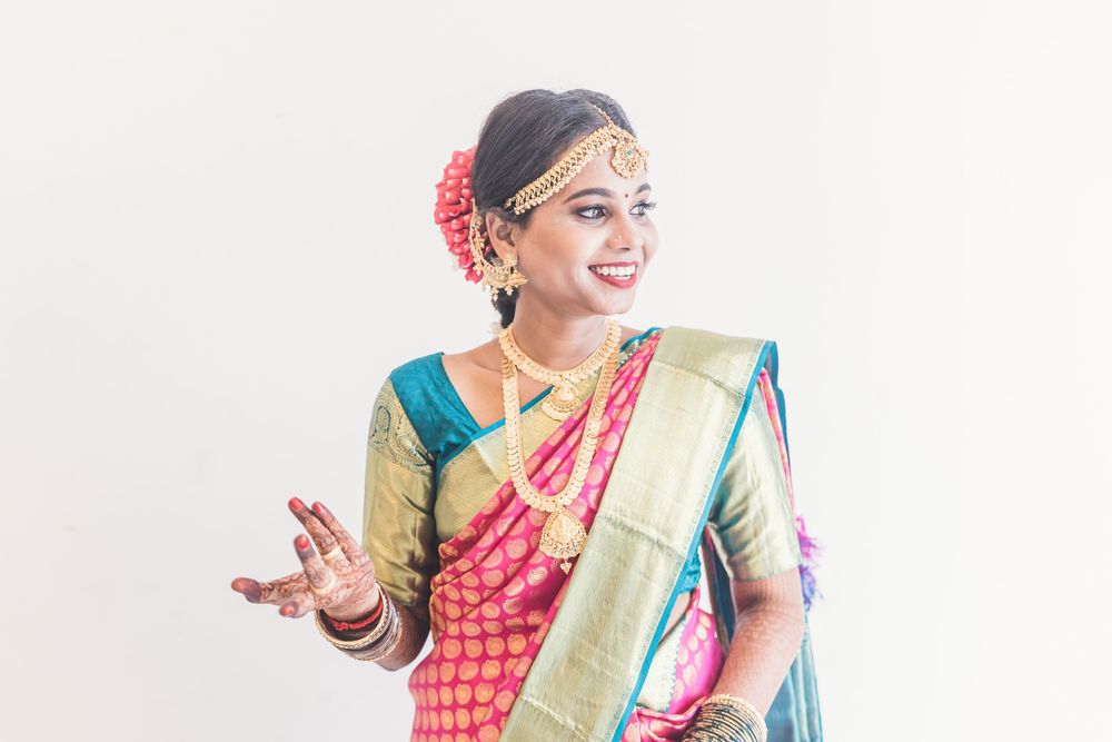 Woman wearing traditional silk saree with gold border and jewelry gesturing expressively.