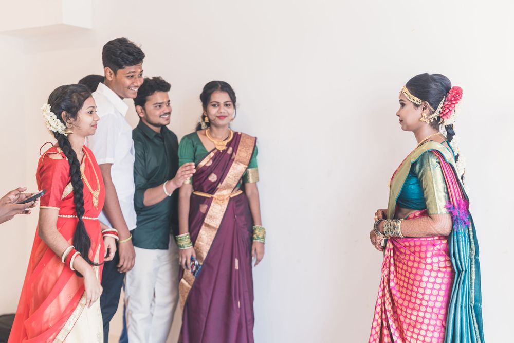 Group of people in traditional Indian attire standing against white wall during celebratory gathering.