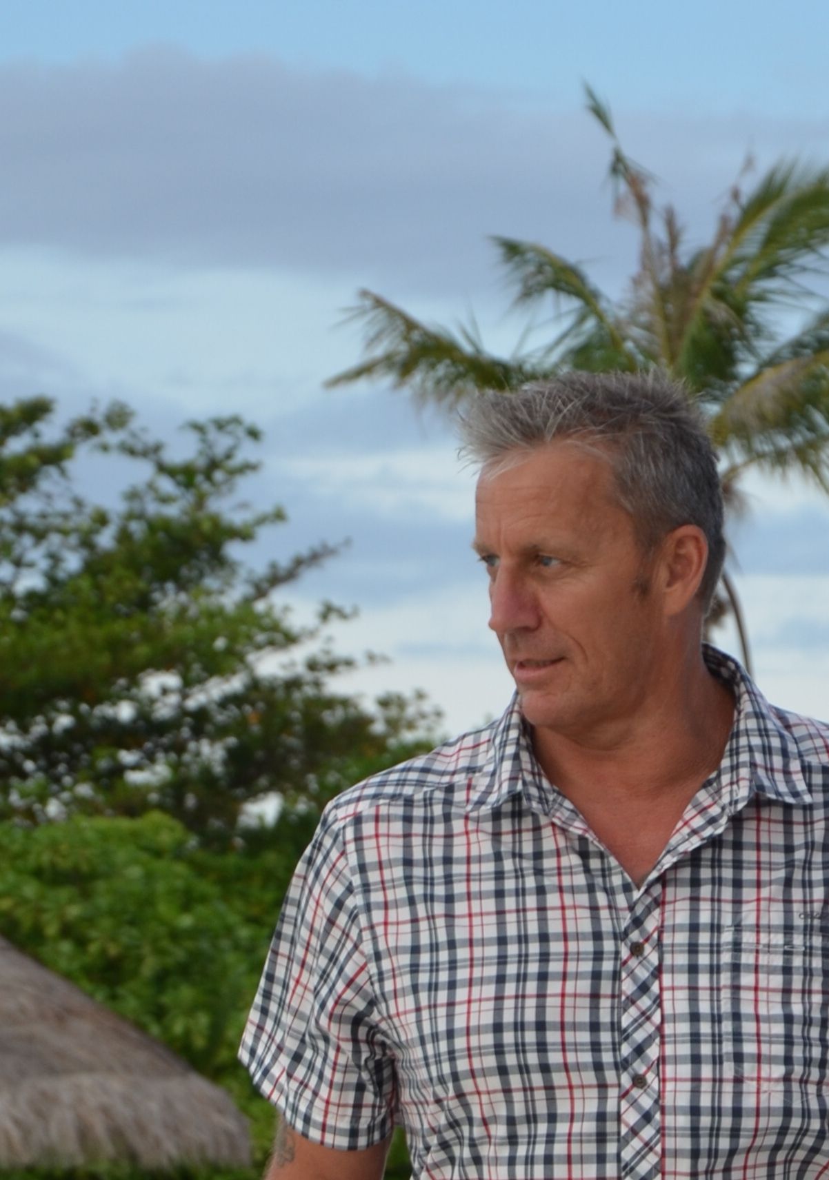 Outdoor portrait with palm trees and tropical landscape in background.