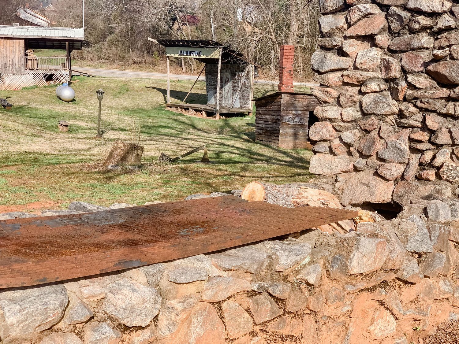 Stone foundation ruins with rustic wooden beams in a grassy field.