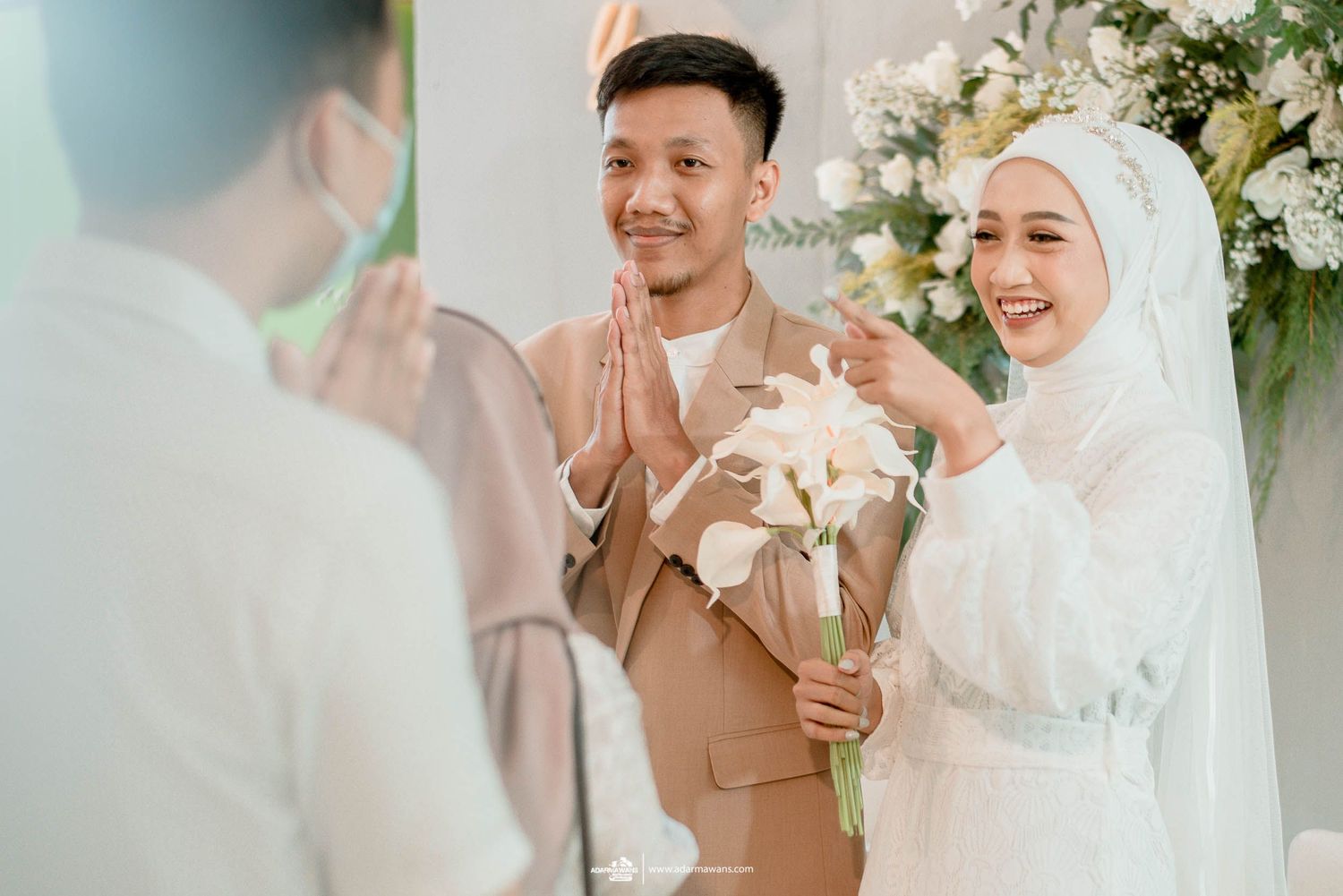 A wedding celebration moment with the couple in beige and white receiving congratulations.
