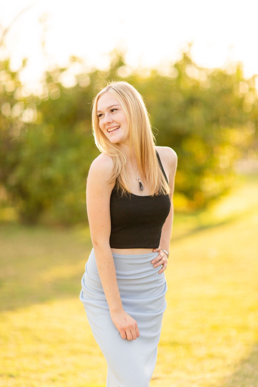 Outdoor portrait in black crop top and light skirt during sunset.