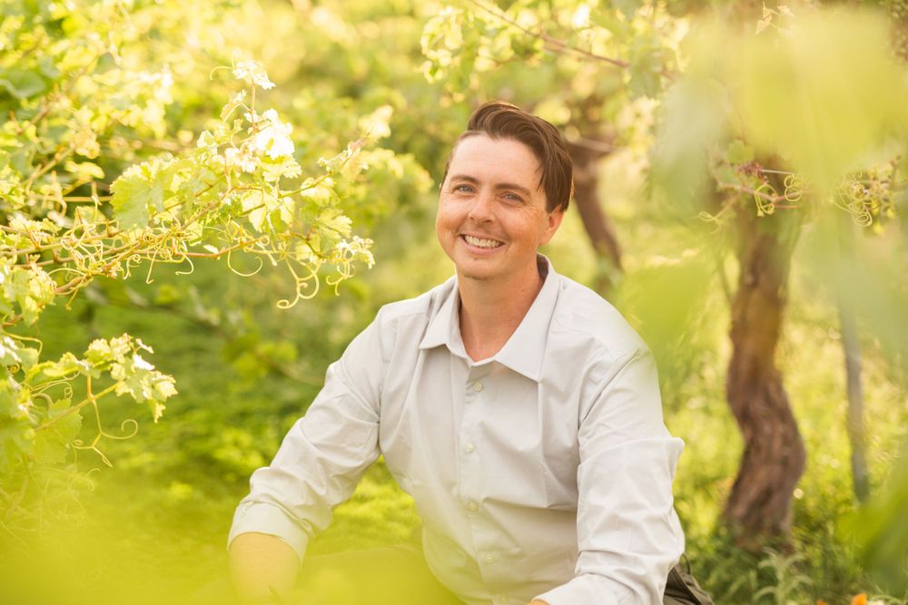 Portrait in garden setting with spring blossoms and natural sunlight filtering through foliage.