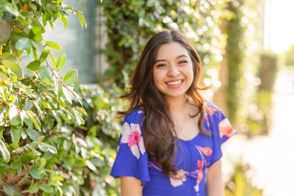Outdoor portrait in blue floral dress with natural greenery background.