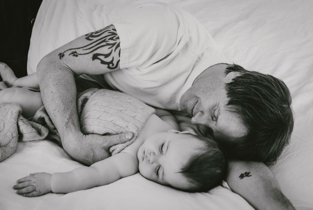 Black and white intimate photo of parent and child resting on bed.