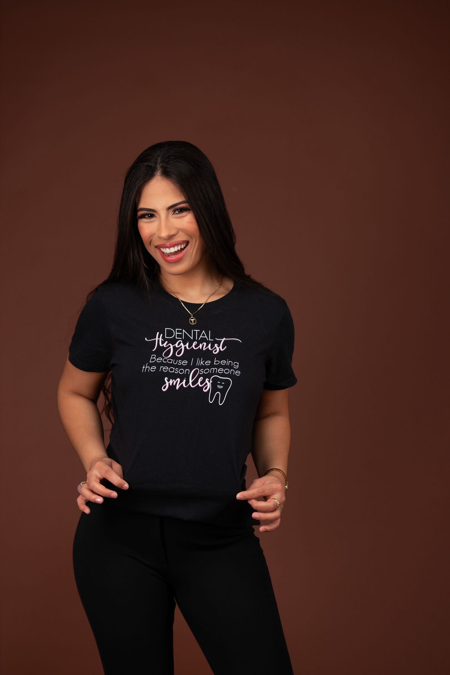 Healthcare professional wearing a black printed t-shirt smiles in studio portrait.