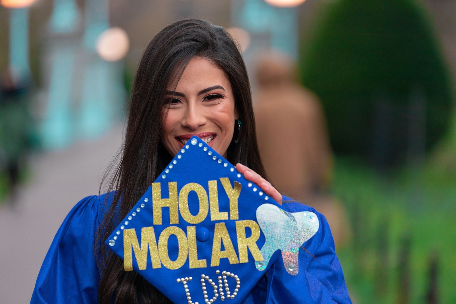 Graduate showing off custom Holy Molar dental school graduation cap with bright smile.