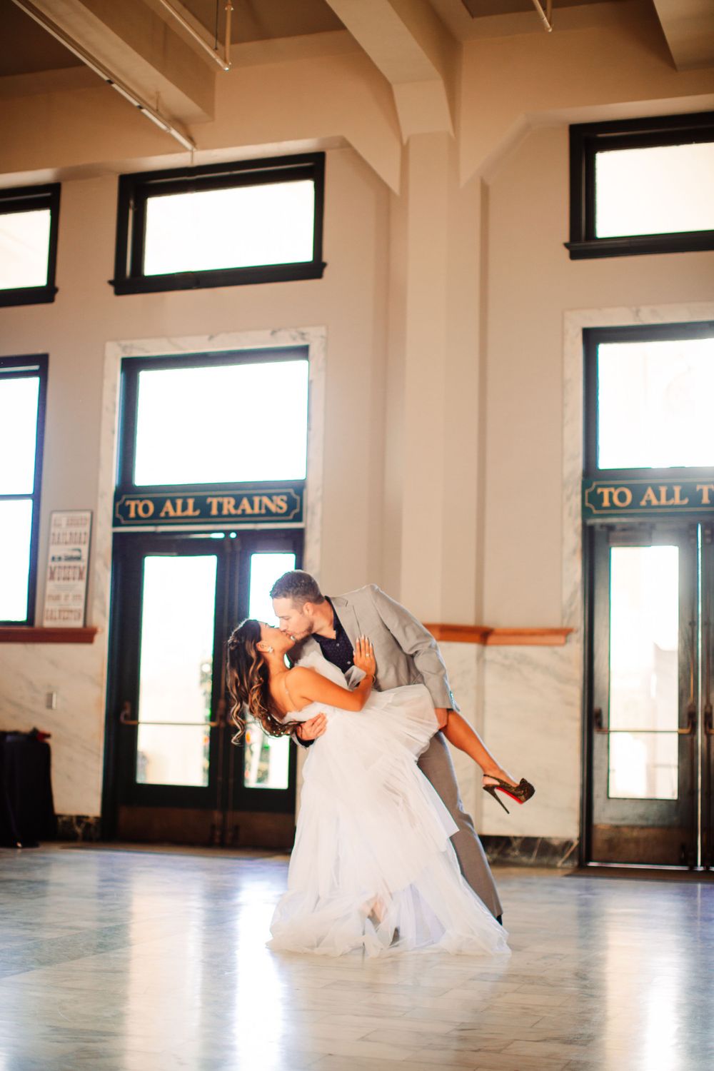 Couple performs romantic dance dip in front of train station doors.