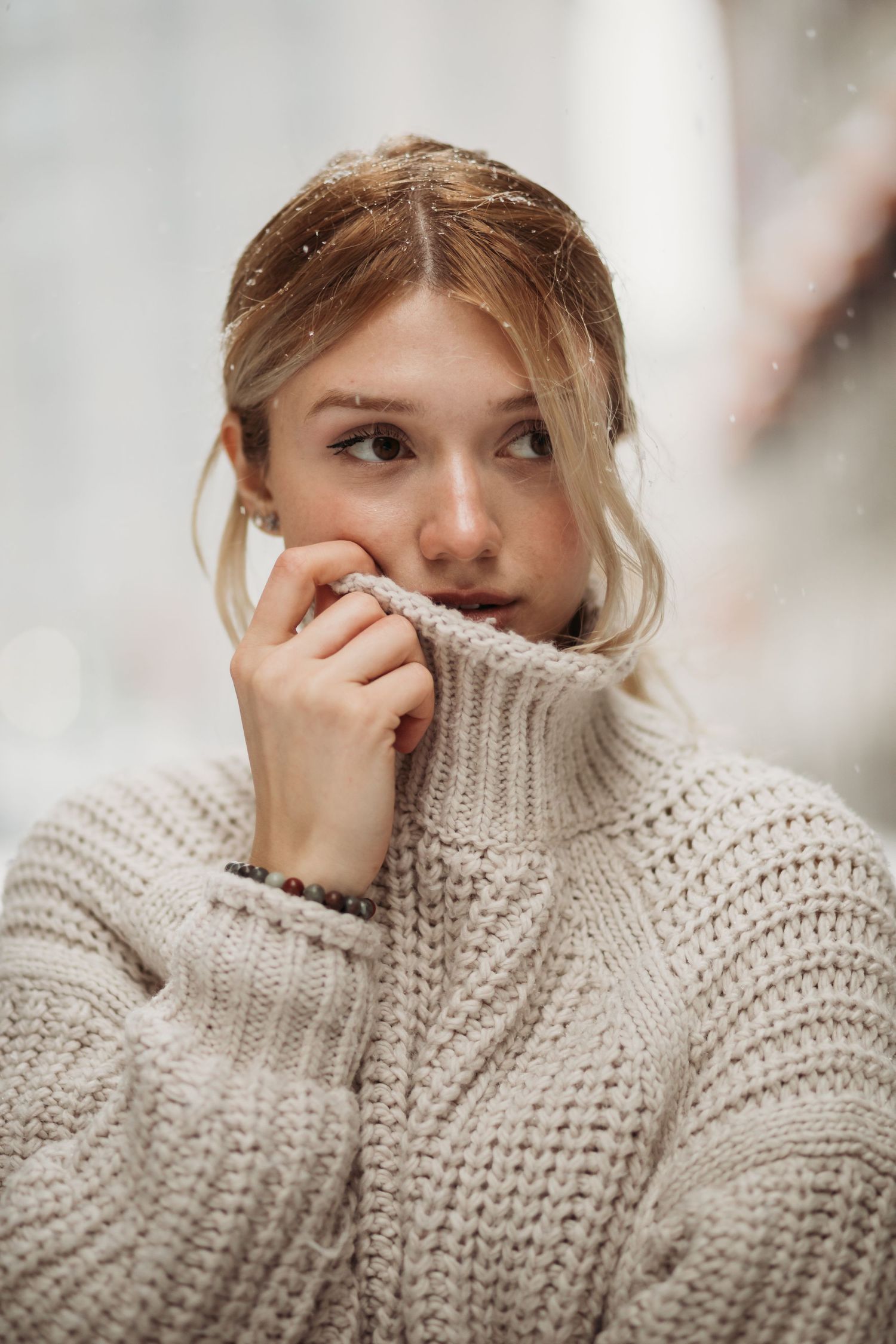 Cozy winter portrait with model in chunky knit sweater looking thoughtful.