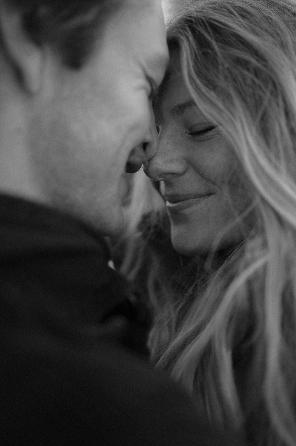 An intimate black and white close-up portrait capturing a tender romantic moment.
