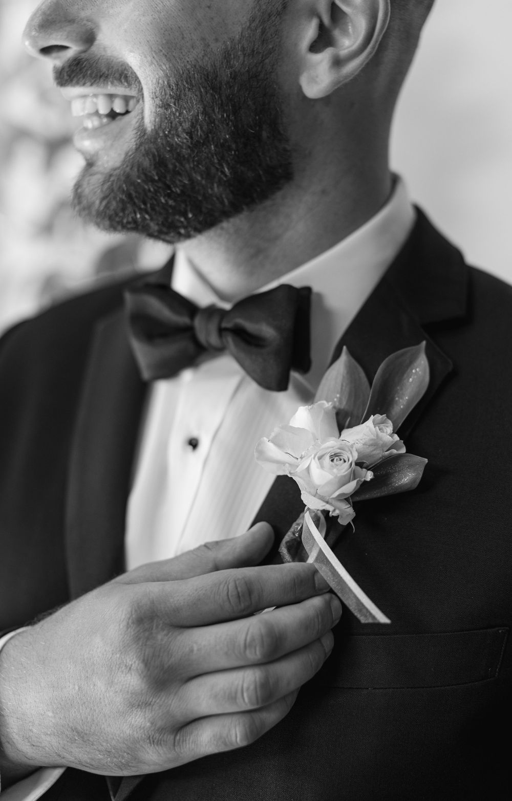 Close up of formal suit with black bow tie and white rose boutonniere.